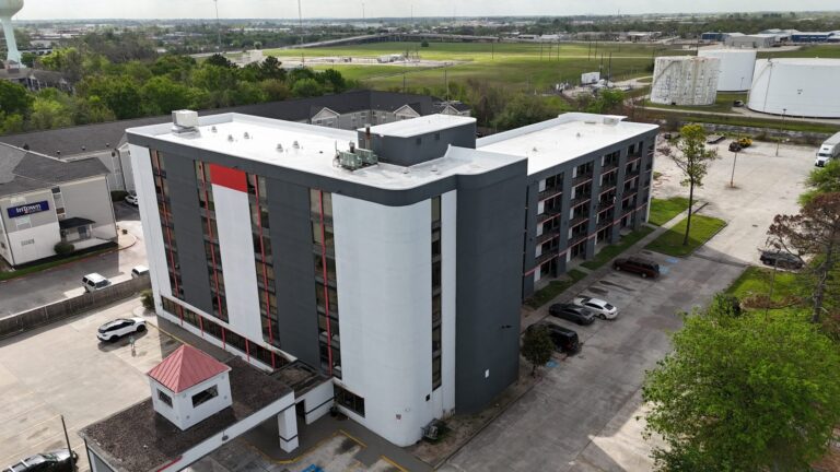 Aerial view of a commercial building with a newly completed white flat roof