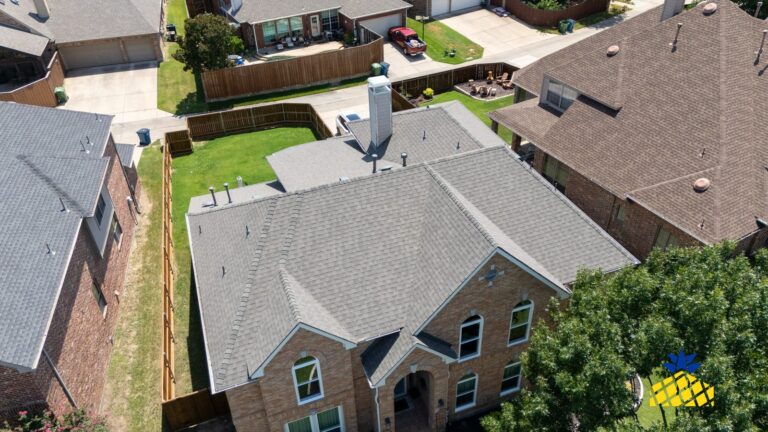Aerial view of a brick two-storey home with a grey shingle roof in Lewisville, TX
